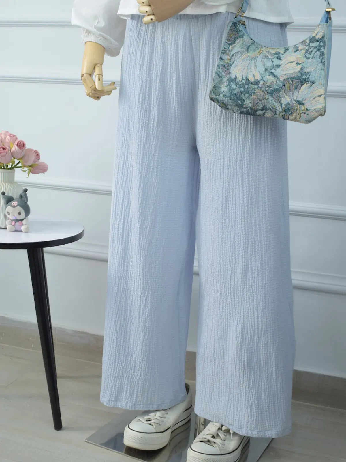 Marina textured blue wide-leg pants front close view on mannequin – elasticated waist, side pocket, paired with white top and floral tapestry shoulder bag