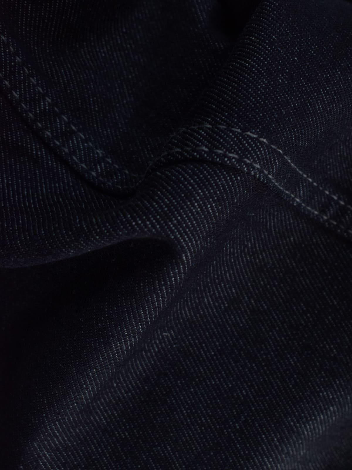 Close-up texture shot of dark navy denim fabric with contrast stitching detail