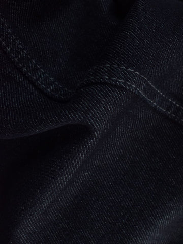 Close-up texture shot of dark navy denim fabric with contrast stitching detail