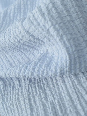 Marina pastel blue textured fabric close-up – soft crinkled breathable texture with subtle grid weave pattern and gentle drape