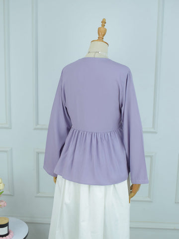 Lavender blouse on a mannequin against a light blue wall.