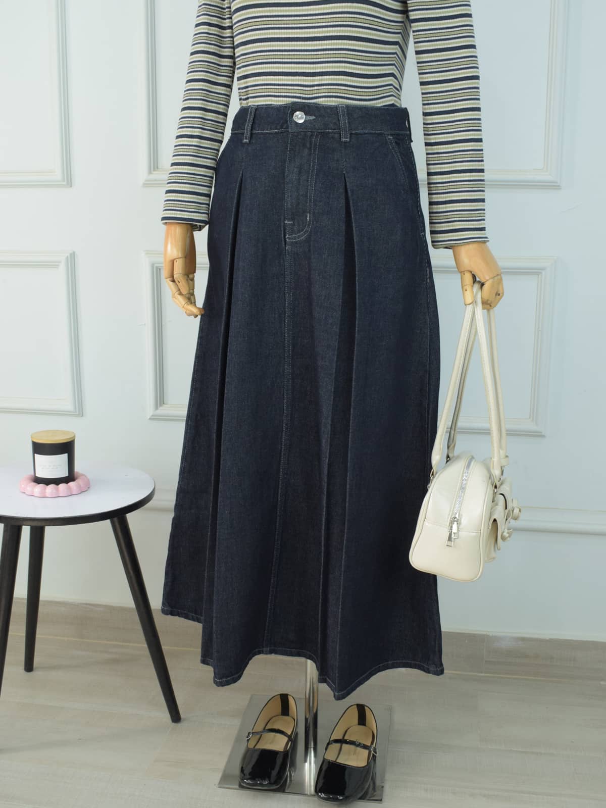 Front close-up of flared denim maxi skirt showing pleated A-line silhouette and waistband detail on mannequin