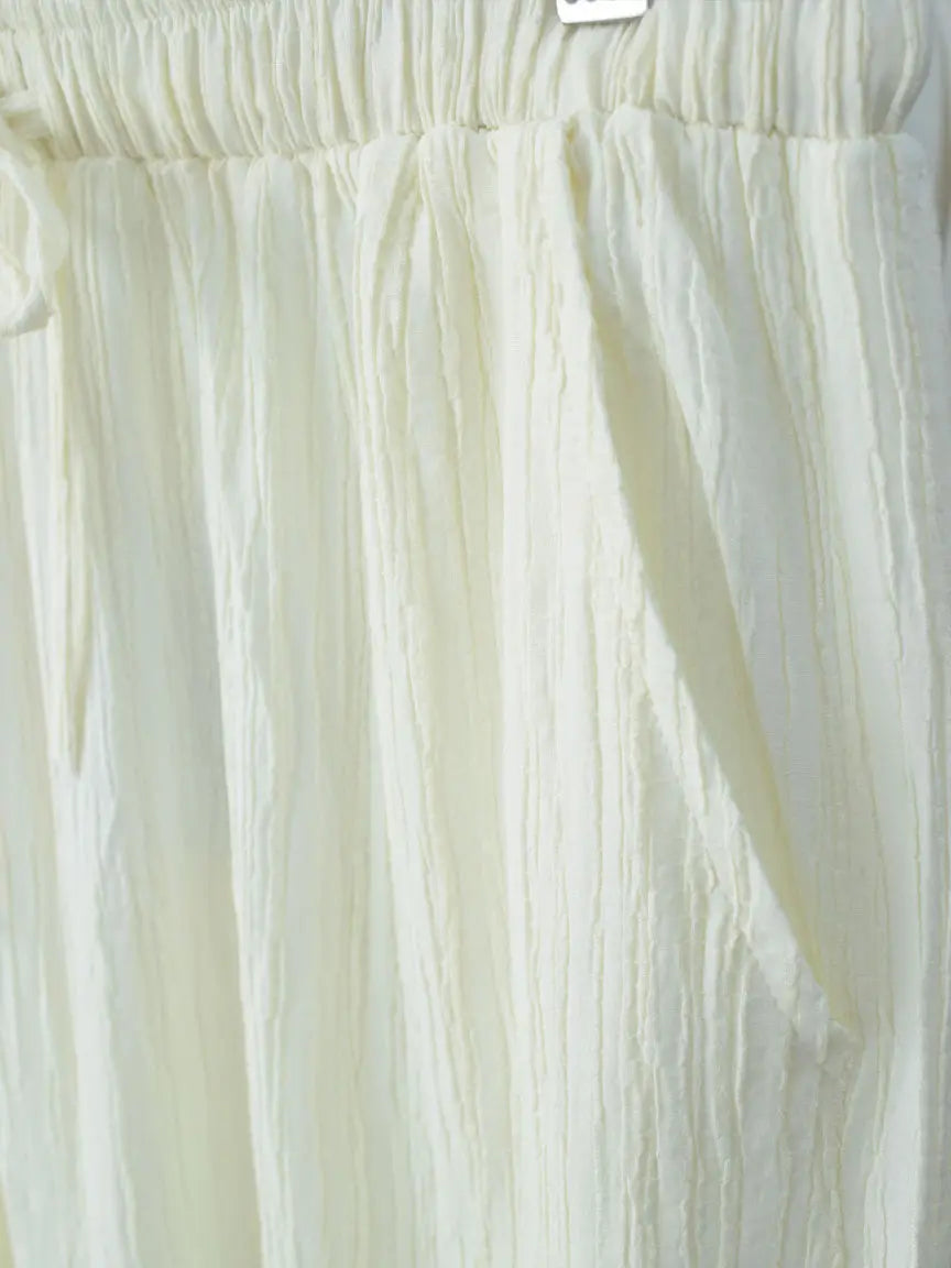 Close-up detail of DOVE textured off-white wide-leg pants