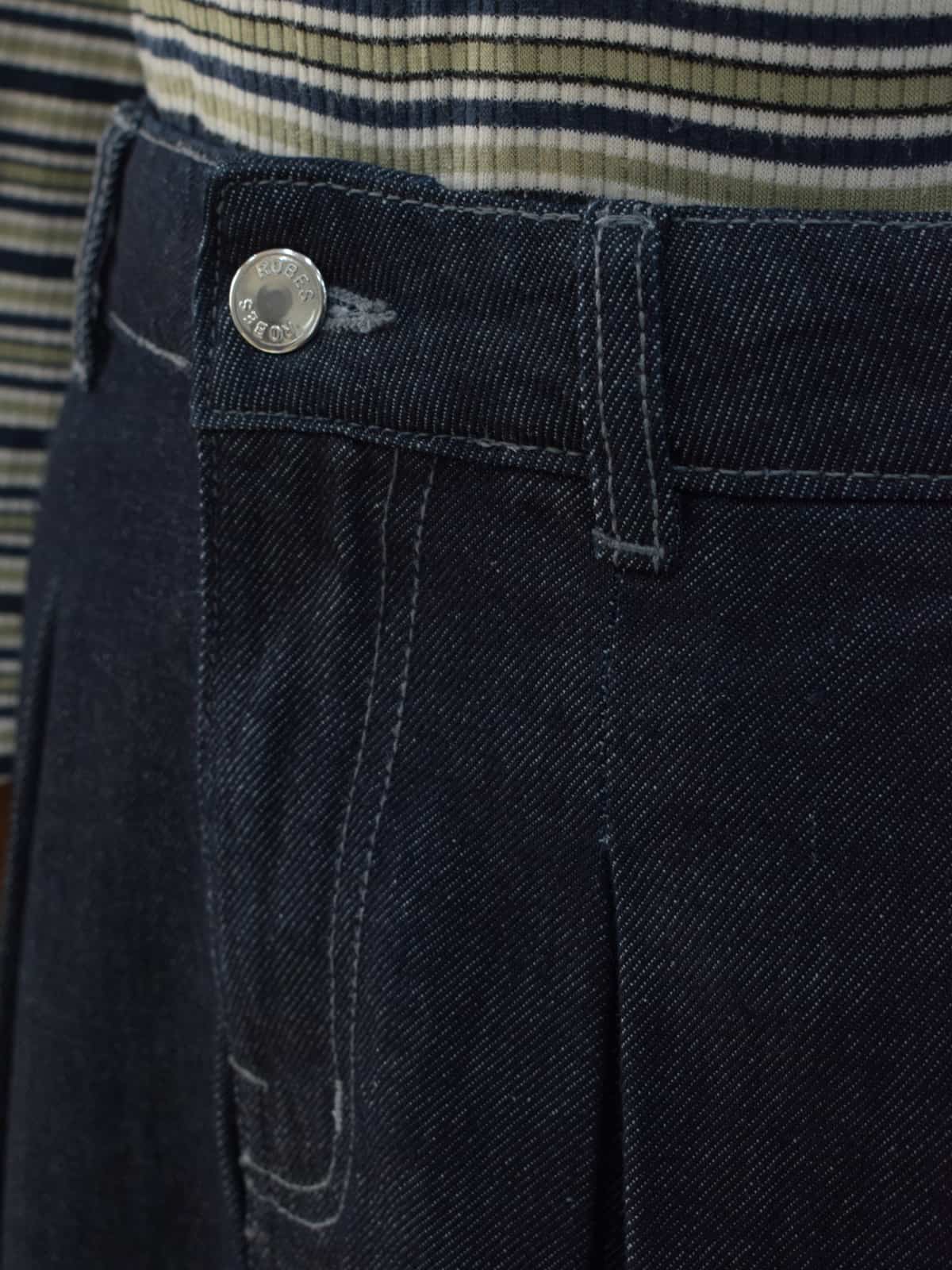 Close-up of denim skirt waistband showing silver button closure and side pocket detail