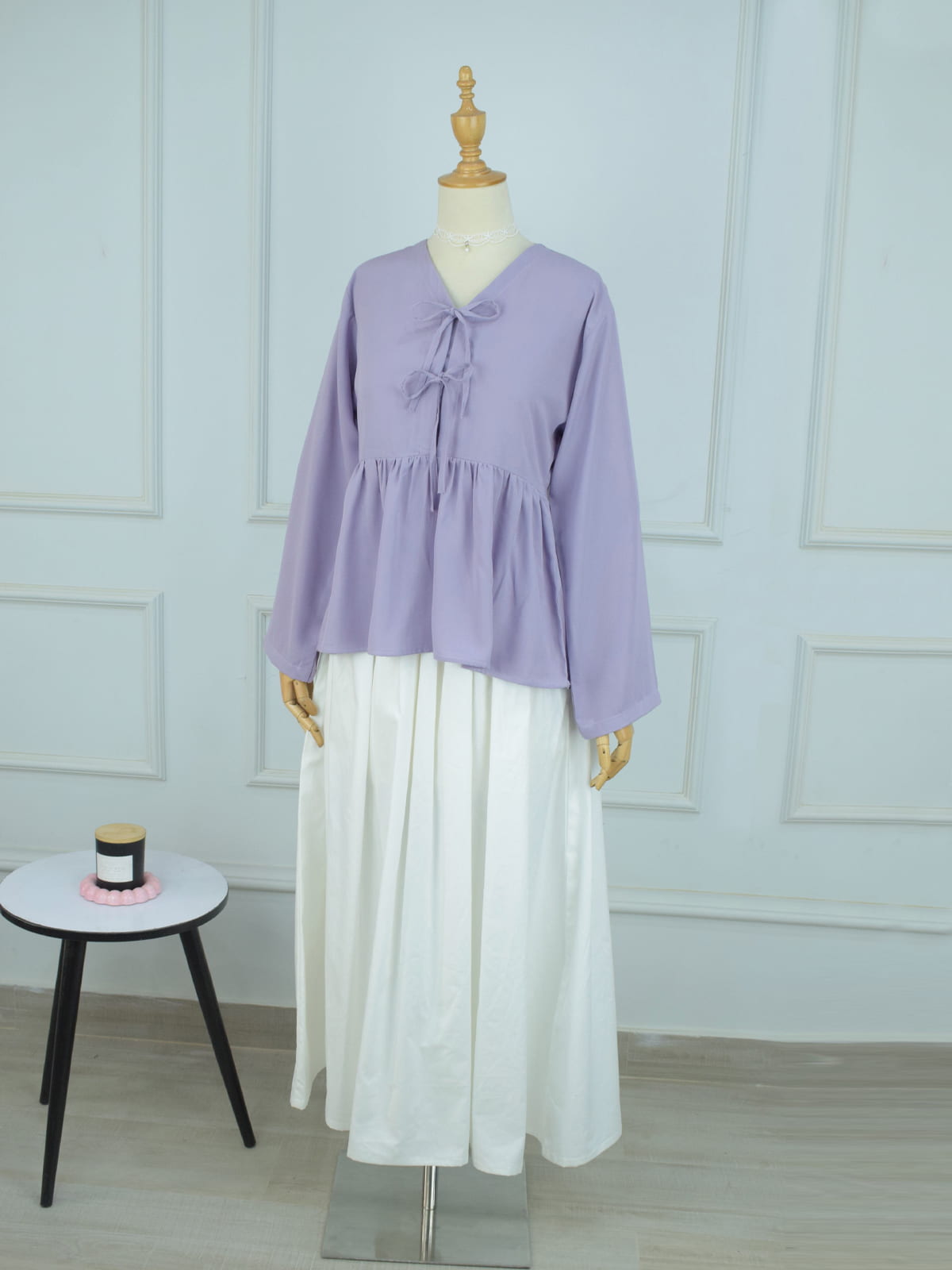 Full length front view of lilac double bow peplum top styled with white flowy skirt on mannequin