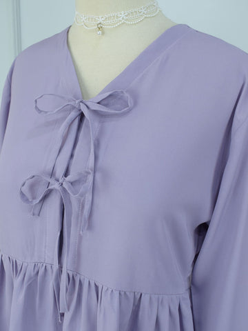 Close-up of lilac crepe peplum top showing double bow tie closures and gathered waist detail on mannequin