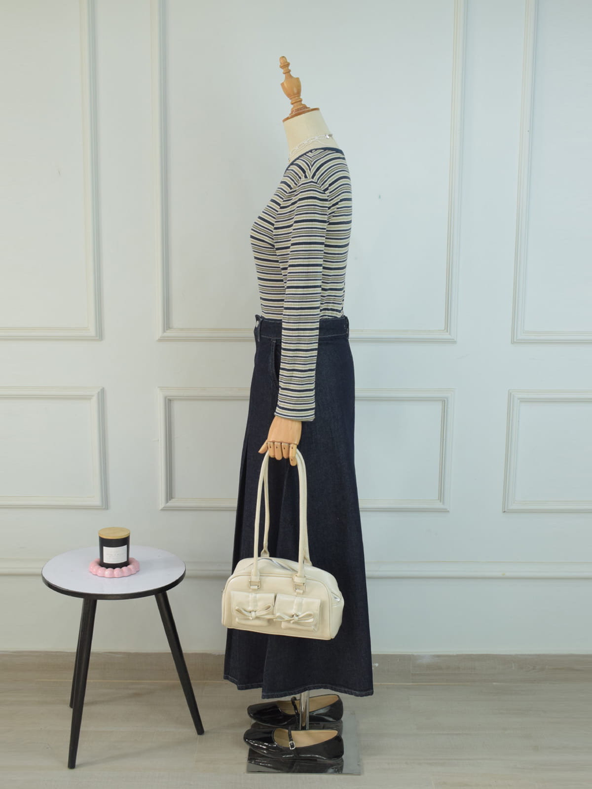 Side profile view of charcoal blue A-line denim maxi skirt styled with striped top and cream bow bag on mannequin