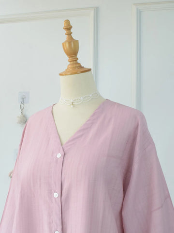 Close-up of V-neckline and upper chest of pink oversized blouse on mannequin