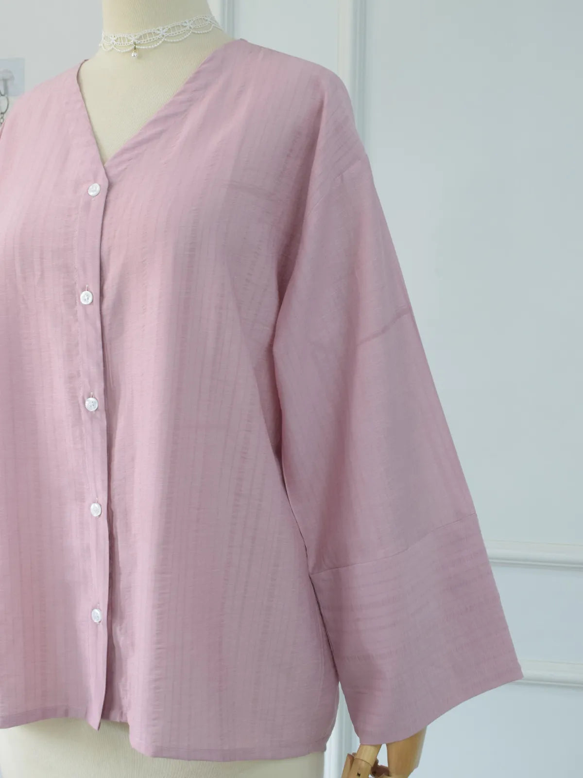 Side angle of pink oversized shirt showing wide sleeve and relaxed fit on mannequin